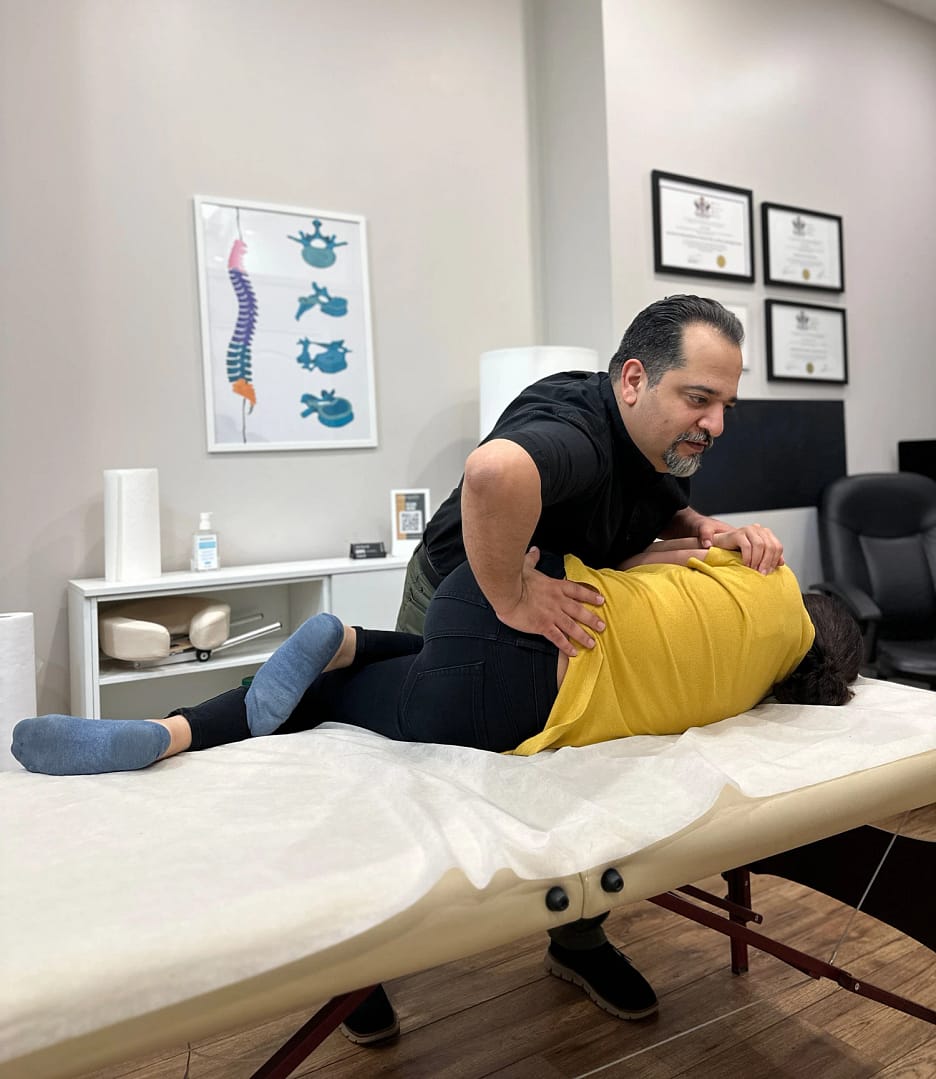 Amir Kazemi, a skilled manual osteopath, providing hands-on treatment to a patient suffering from back pain. Focused on relieving discomfort and restoring mobility through expert osteopathic techniques.